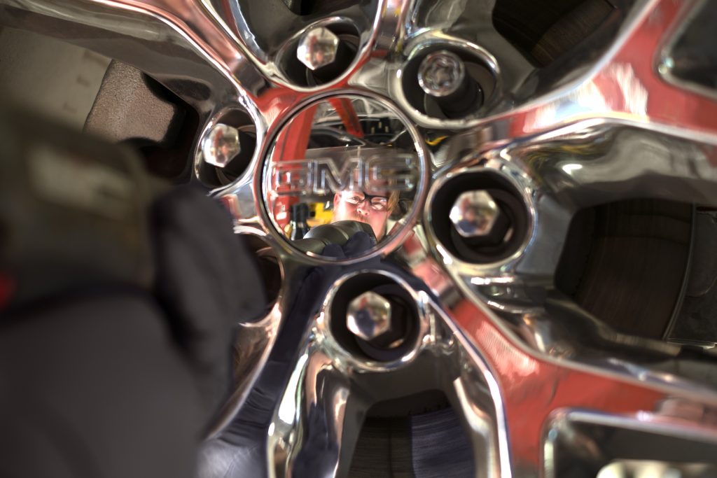 The reflection of a GMC technician in a shiny hub cab after tire service in Carthage, MS 