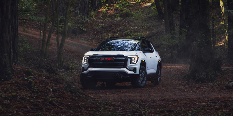 A white GMC SUV driving on a forest trail