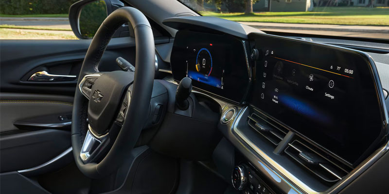 Interior view of a car featuring a steering wheel and two large digital screens on the dashboard